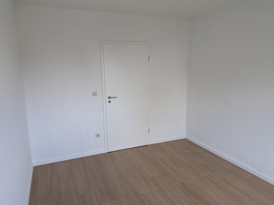 Bodenverlegung Leere, helle Raum mit Holzfußboden und geschlossener Tür.