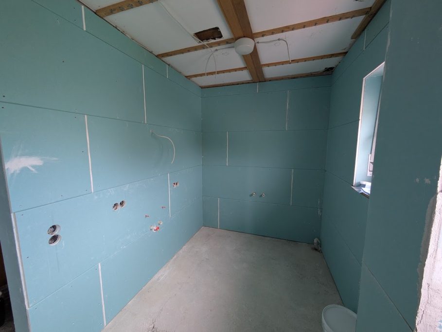 Trockenbau Rohbau eines Raums mit blauen Wänden und unvollständigem Bodenbelag.